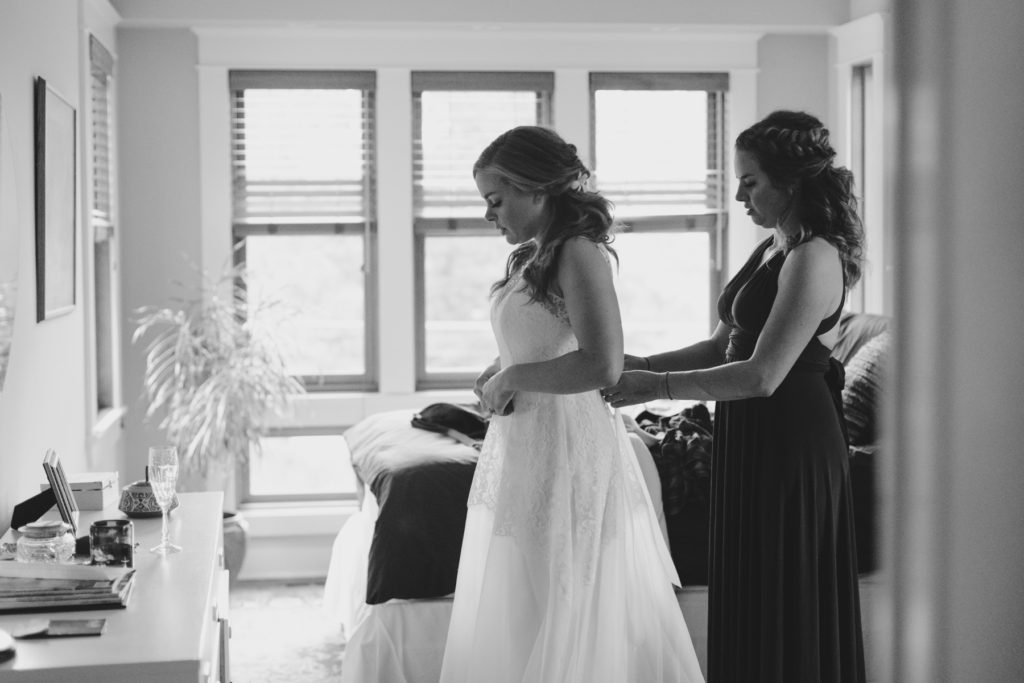 maid of honour helping the bride into her dress