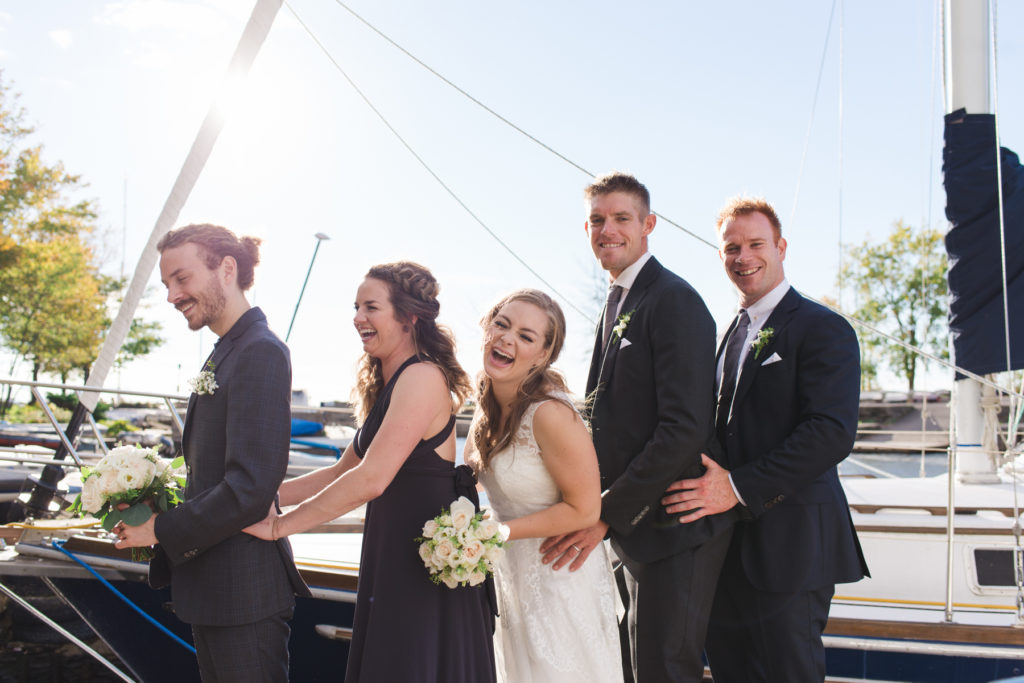 wedding party laughing in front of sail boat