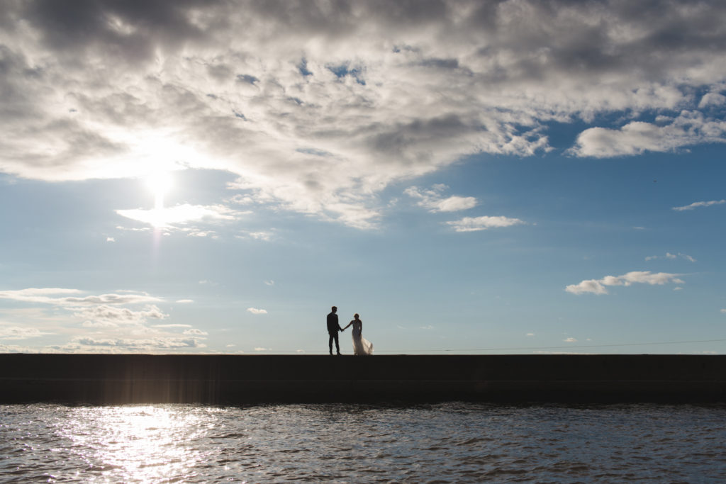 bride and groom standing in pier at yacht club at sunset