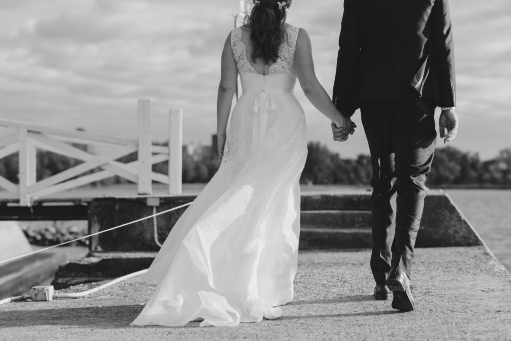 bride and groom holding hands with wind blowing in black and white