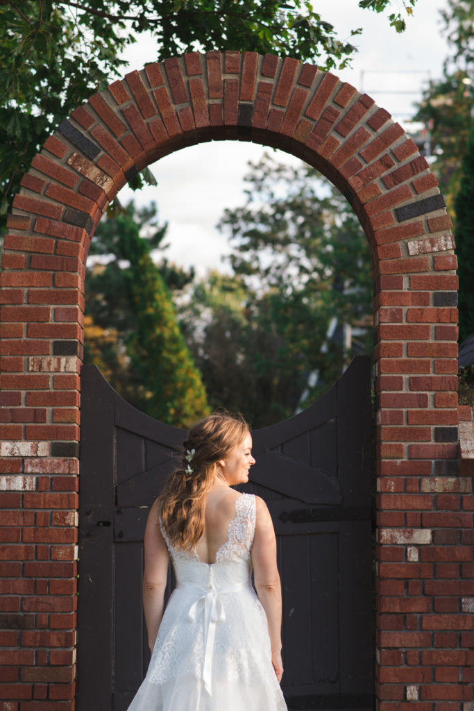 bride standing in front of stone archway