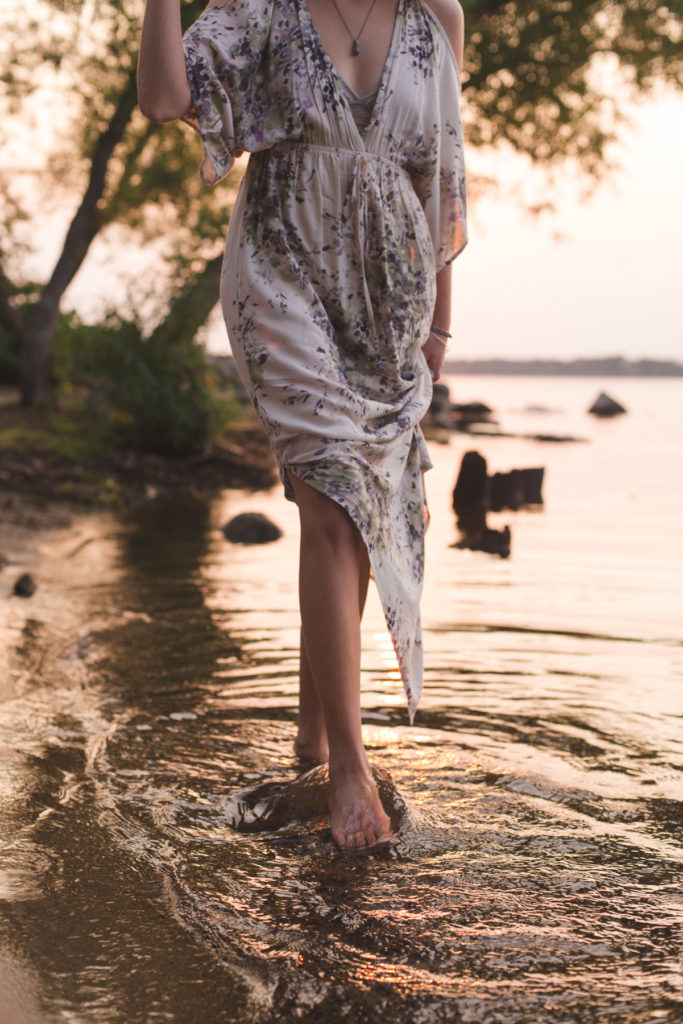 girl walking in water holding flowing dress
