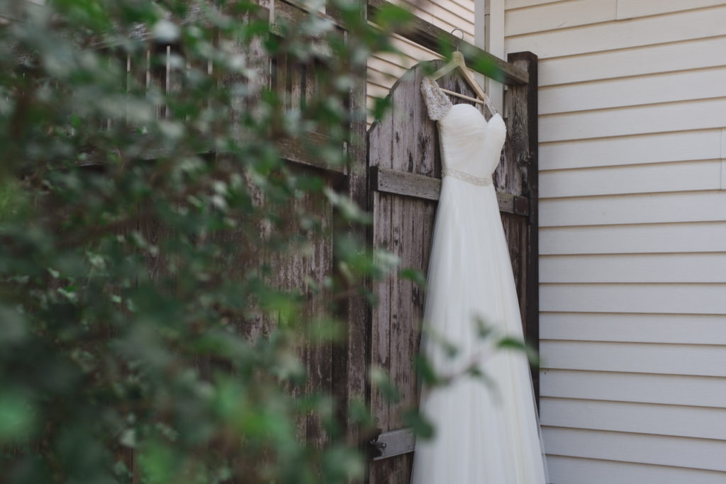 whimsical wedding dress hanging on wooden door
