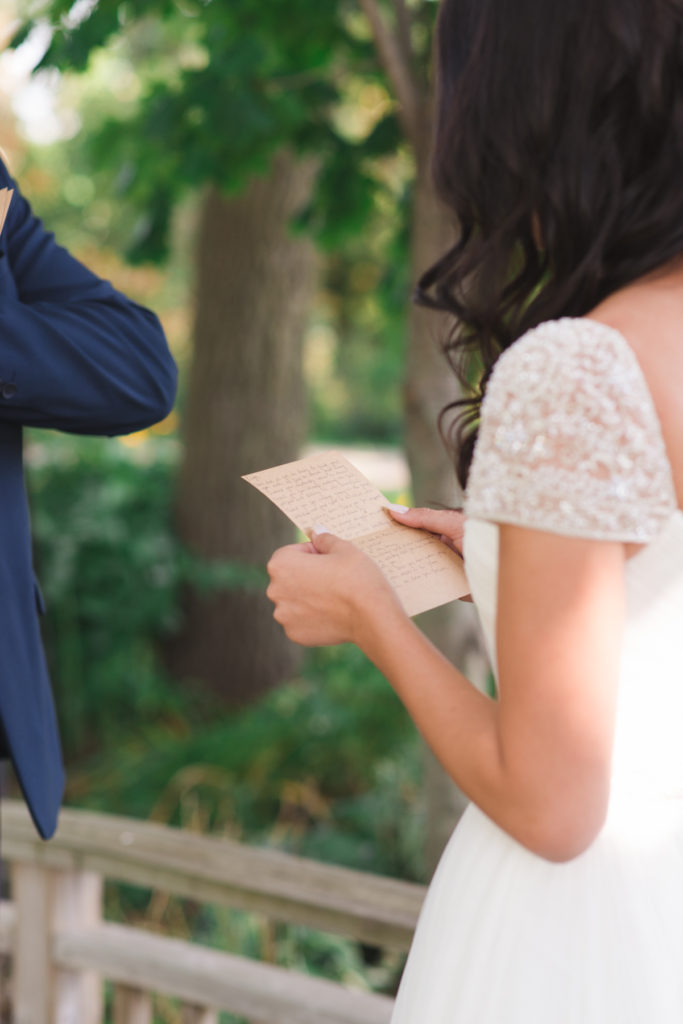 bride and groom reading vows to each other in private