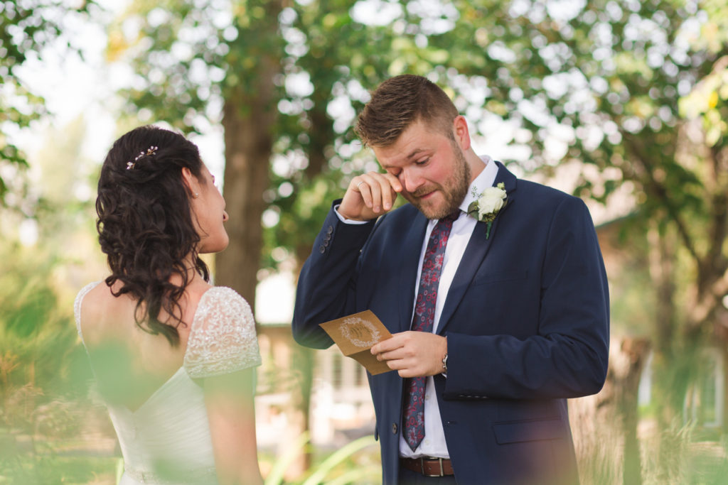 bride and groom reading vows to each other in private