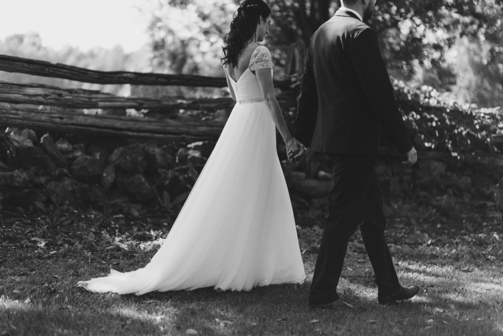 bride and groom walking hand in hand in black and white