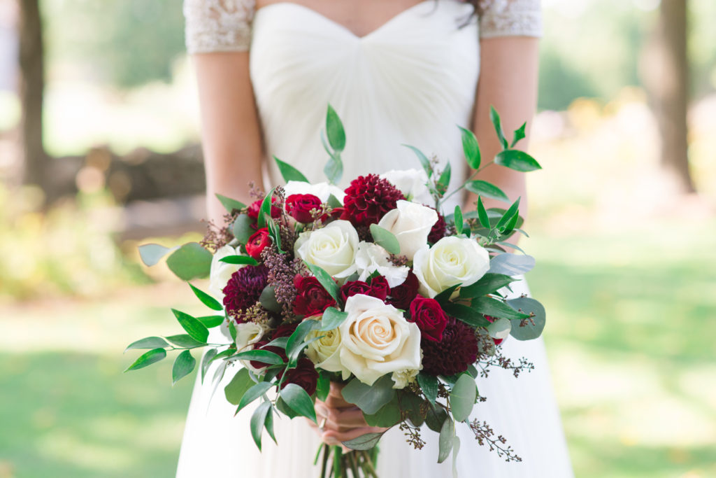 bride holding bouquet of white and red roses