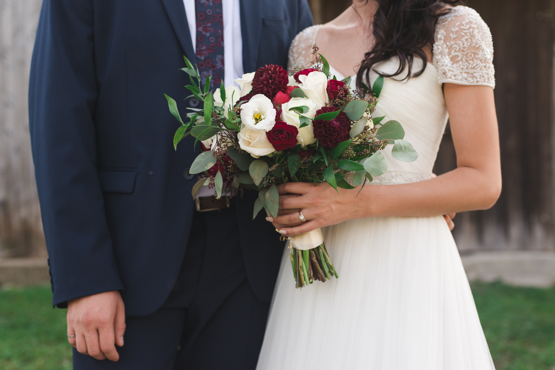 bride holding bouquet of white and red flowers