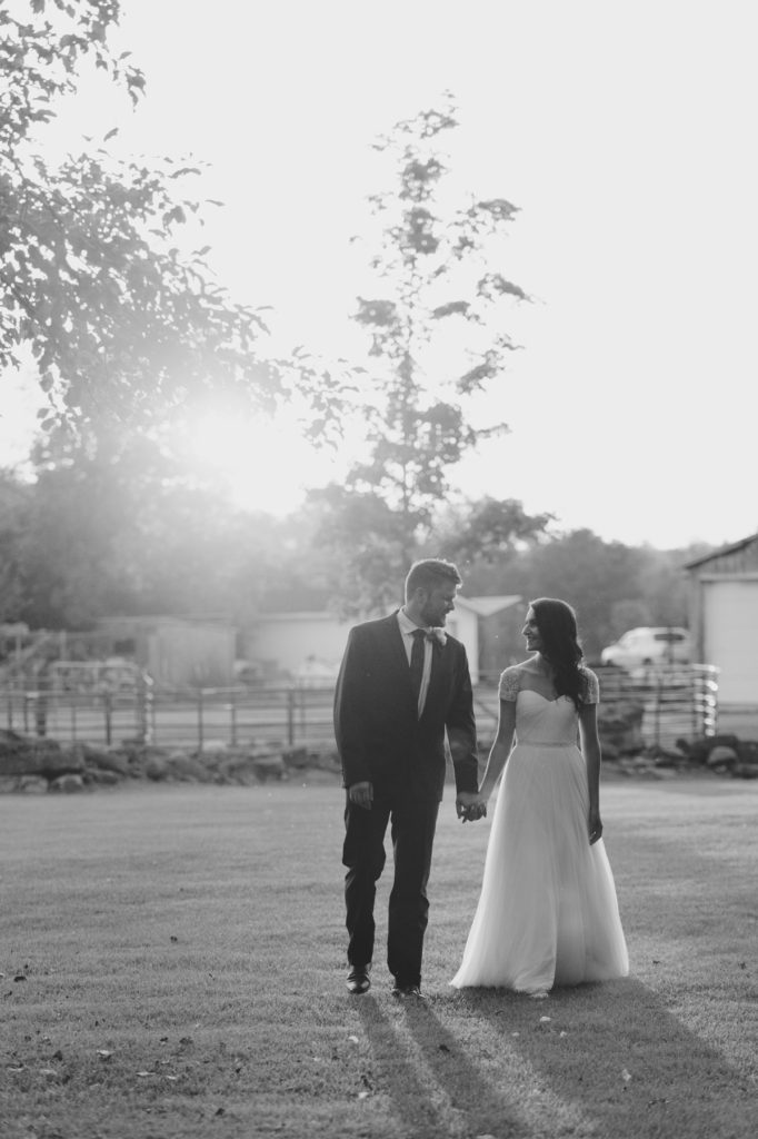 bride and groom walking in farmers field during sunset
