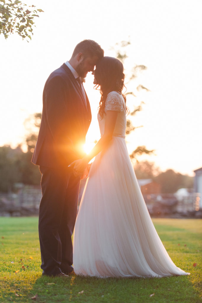 couple standing real close during sunset on farmer's field