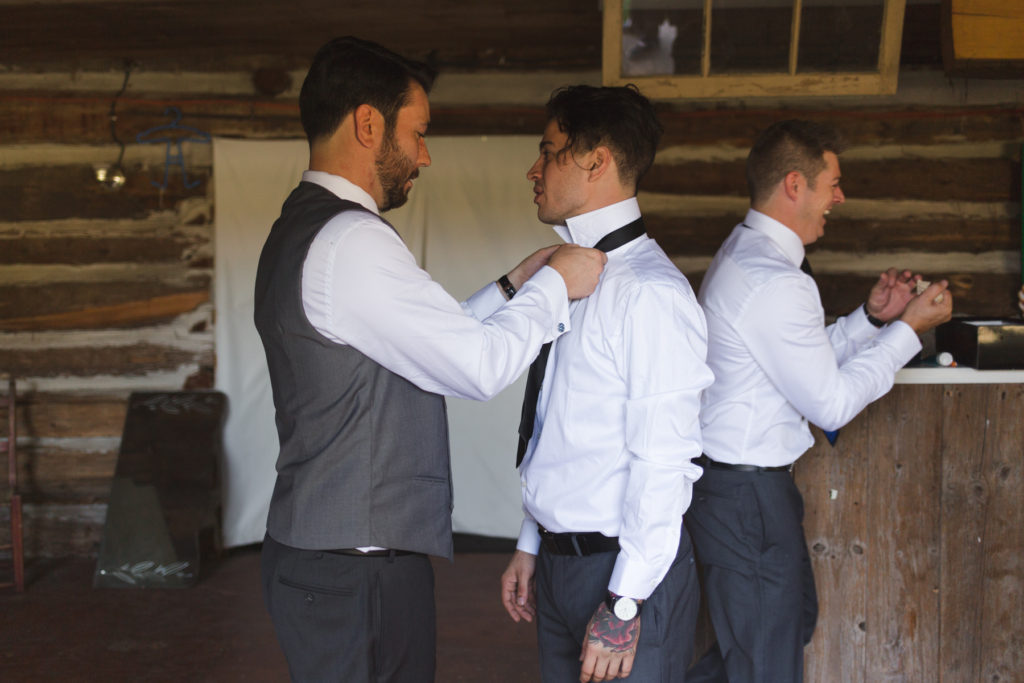 groom helping groomsmen with tie
