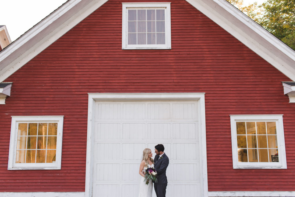 bride and groom in front of red cabin