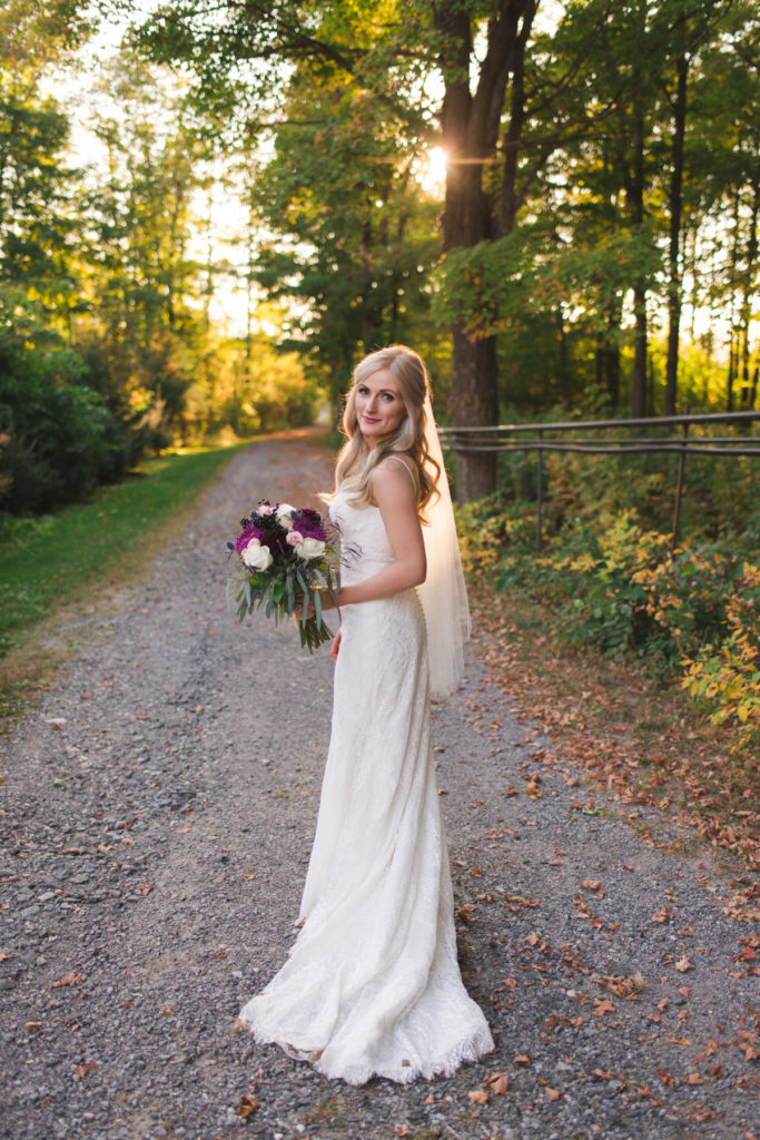 bride standing on dirt road at sunset