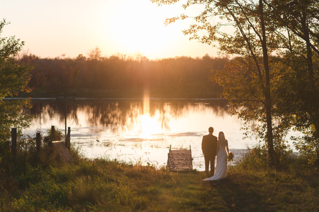 bride and groom by the water at sunset