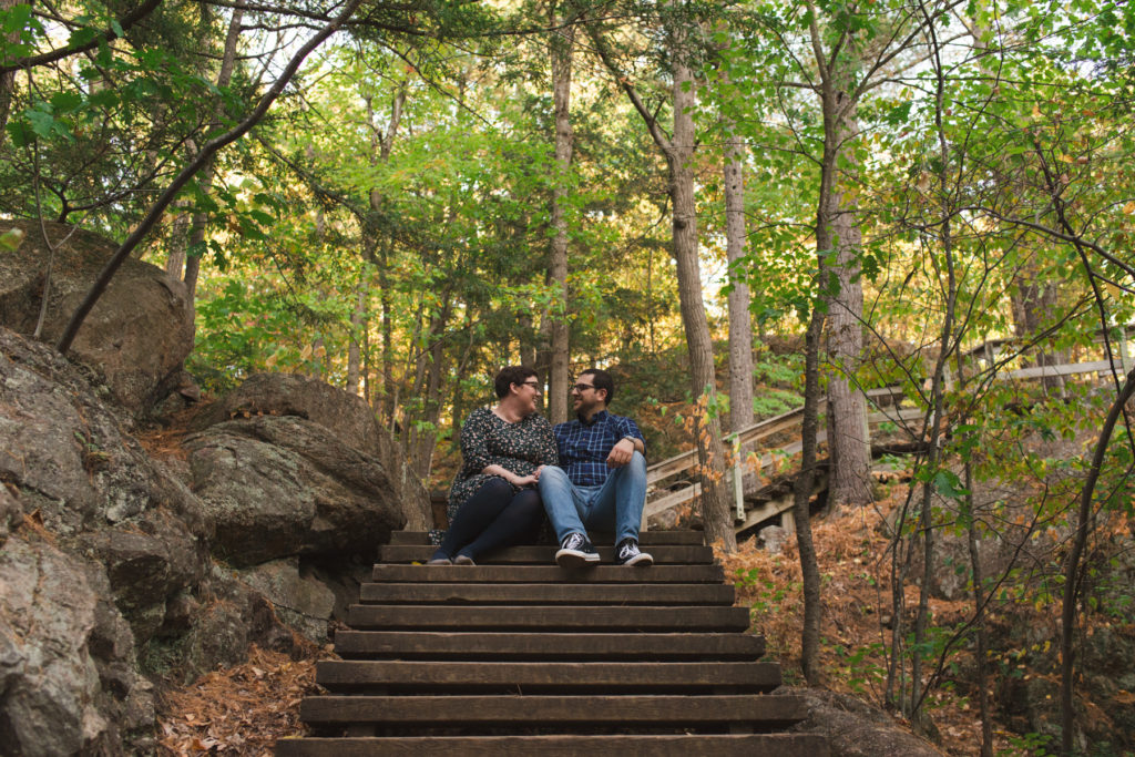 engaged couple sitting on the stairs in the middle of the forest