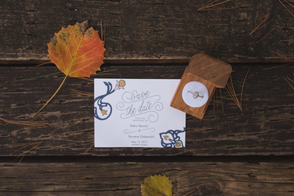 flat lay of save the date and engagement ring with fall leaves