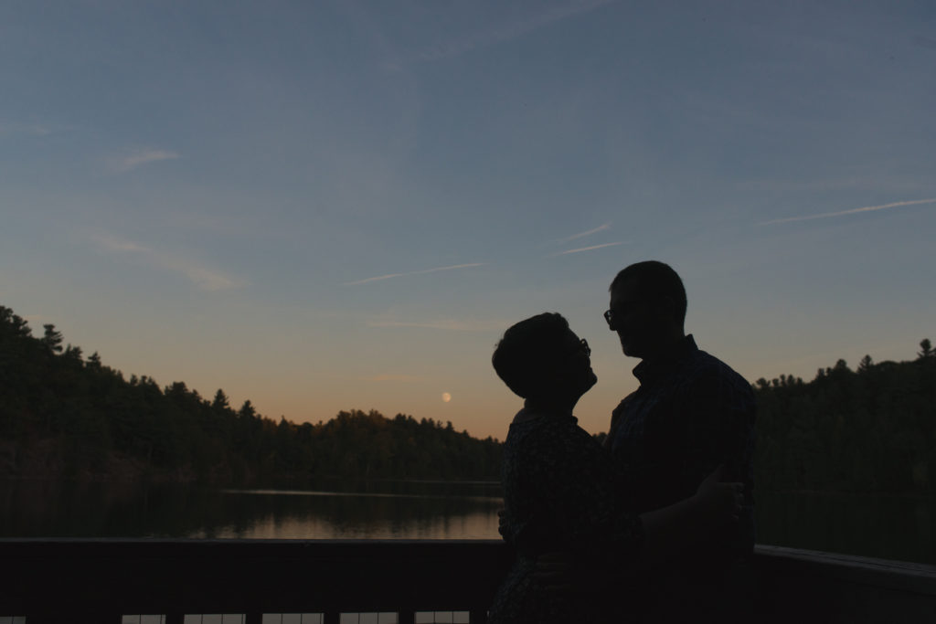 silhouette of engaged couple smiling at sunset by the lake