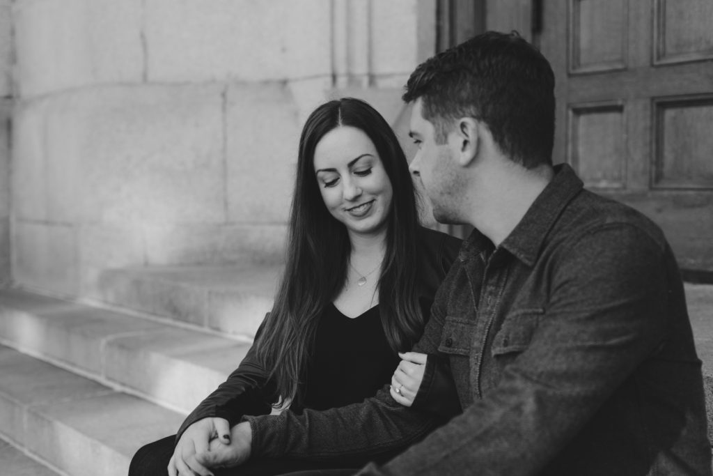 engaged couple sitting on steps holding hands