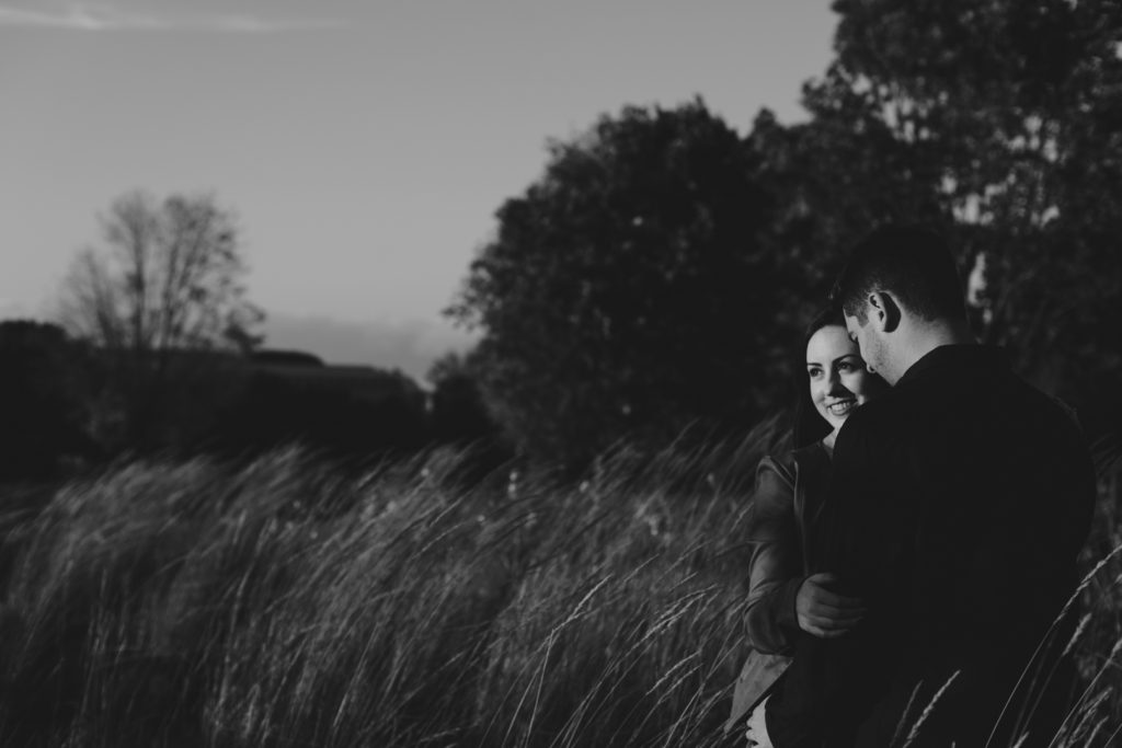 engaged couple looking into the sunset in black and white