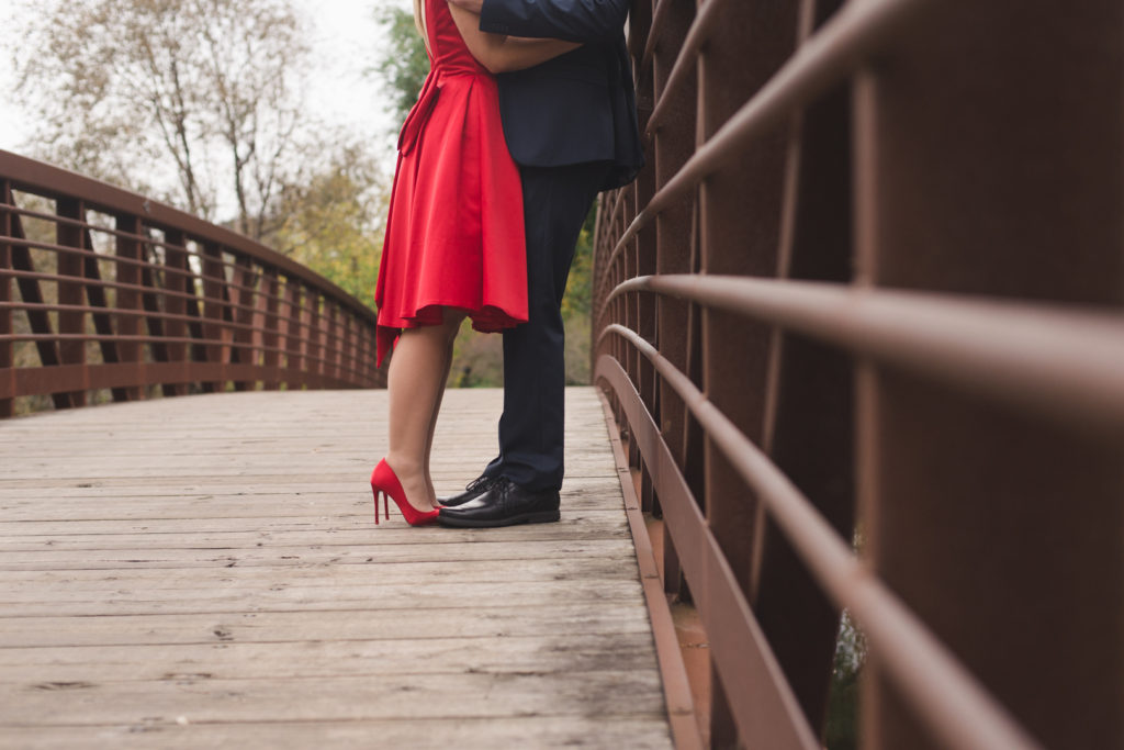engaged couple standing on a bridge hugging