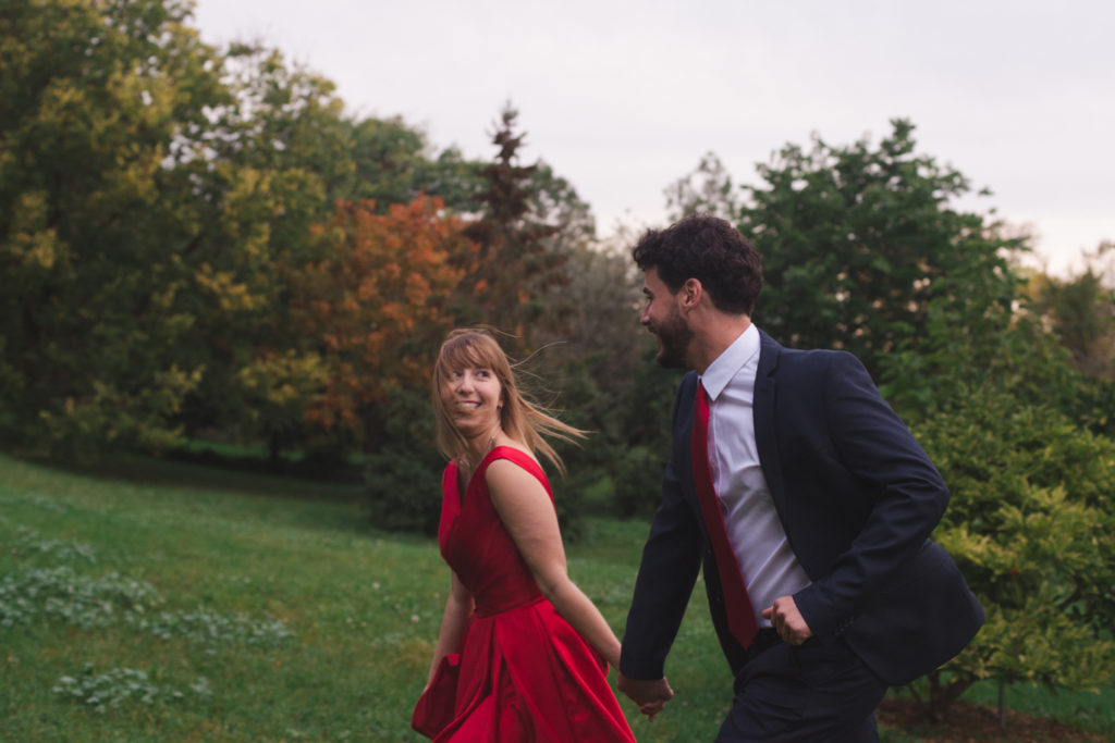 engaged couple running in the grass at sunset