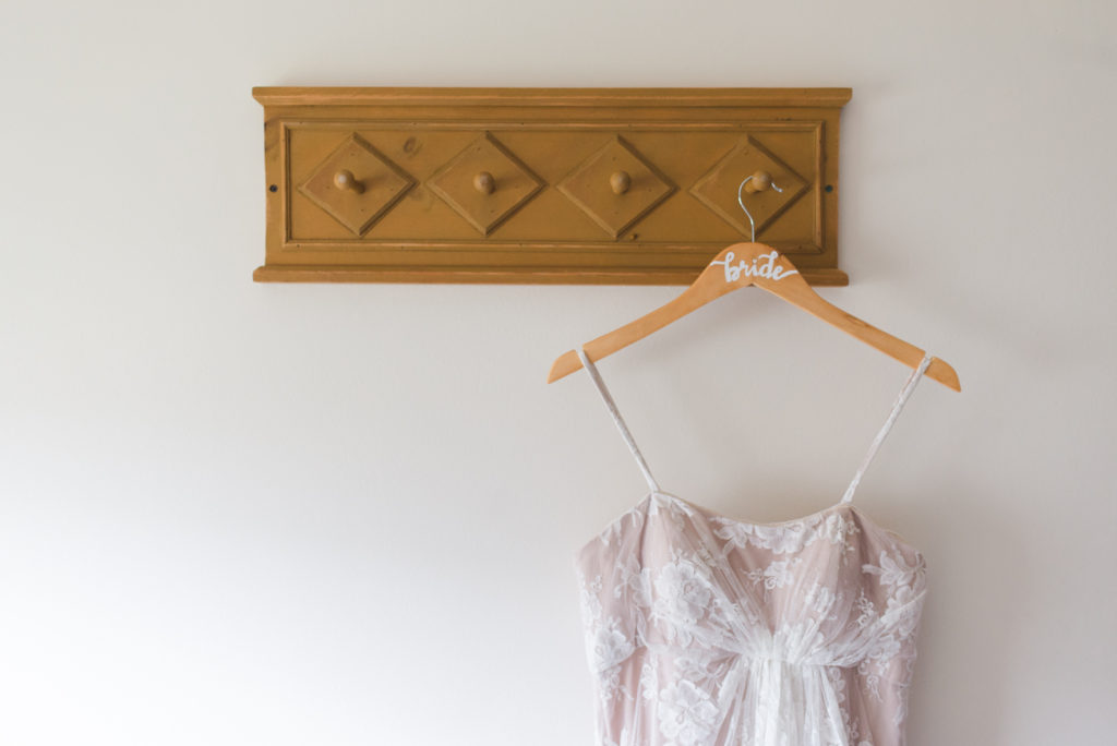 bride's wedding dress hanging on coat hook