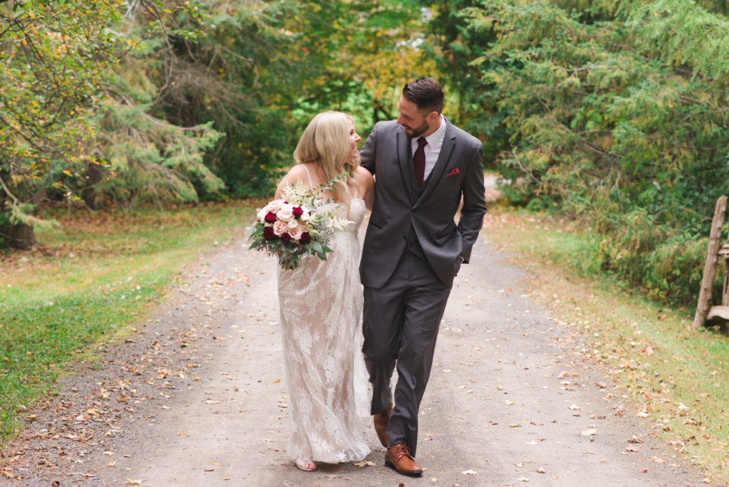 bride and groom walking down a gravel road smiling at each other