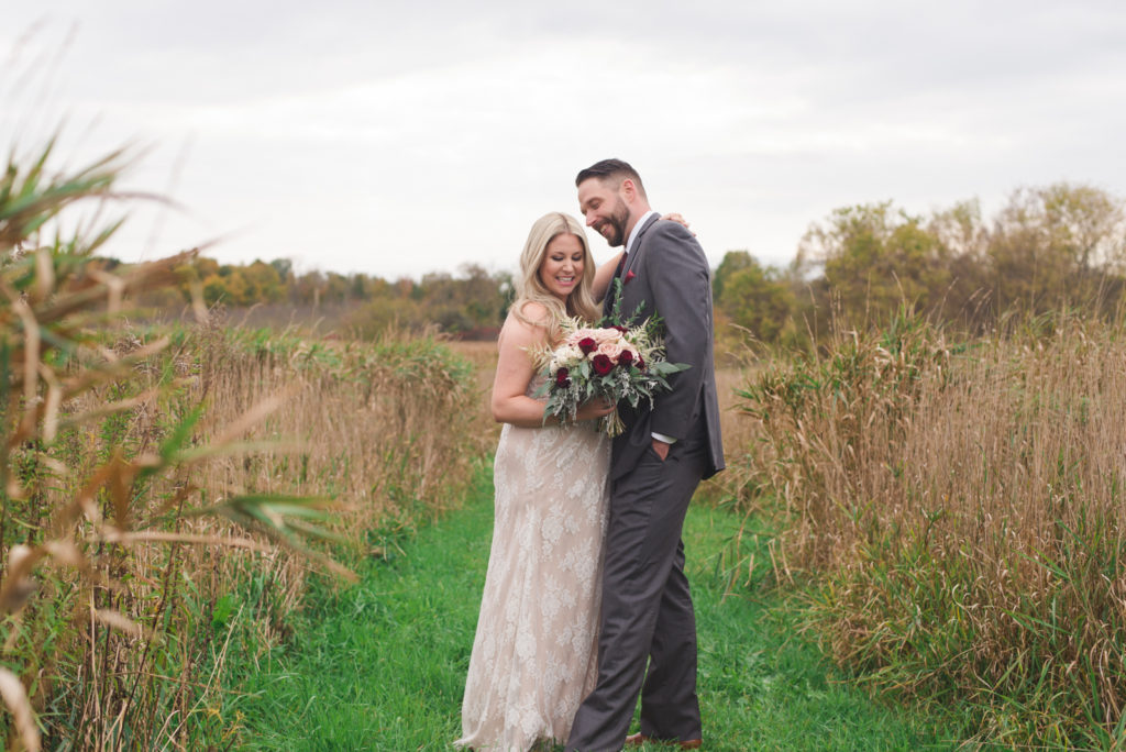bride and groom standing among tall grass in fields of Strathmere
