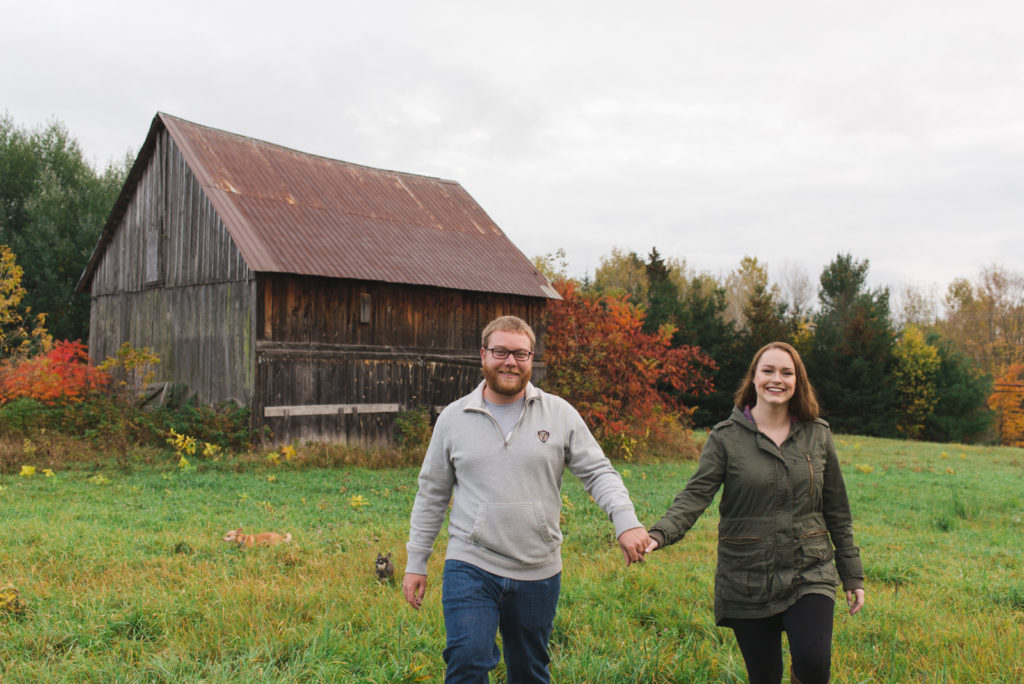 engaged couple holding hands in front of old barn