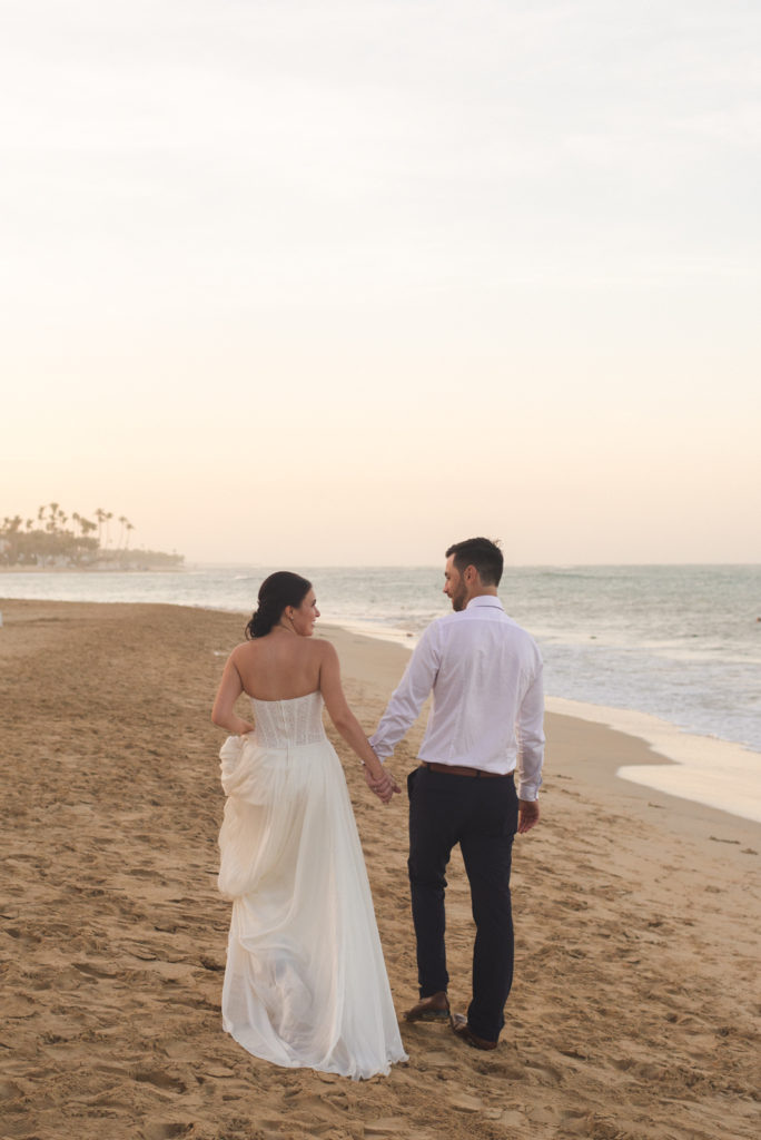 bride and groom walking down the beach at sunset