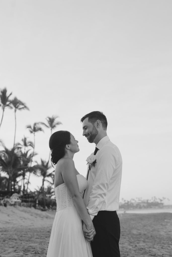 bride and groom smiling on the beach with palm trees