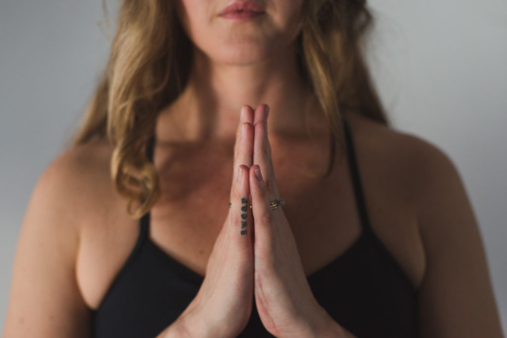 yoga teacher with hands in prayer
