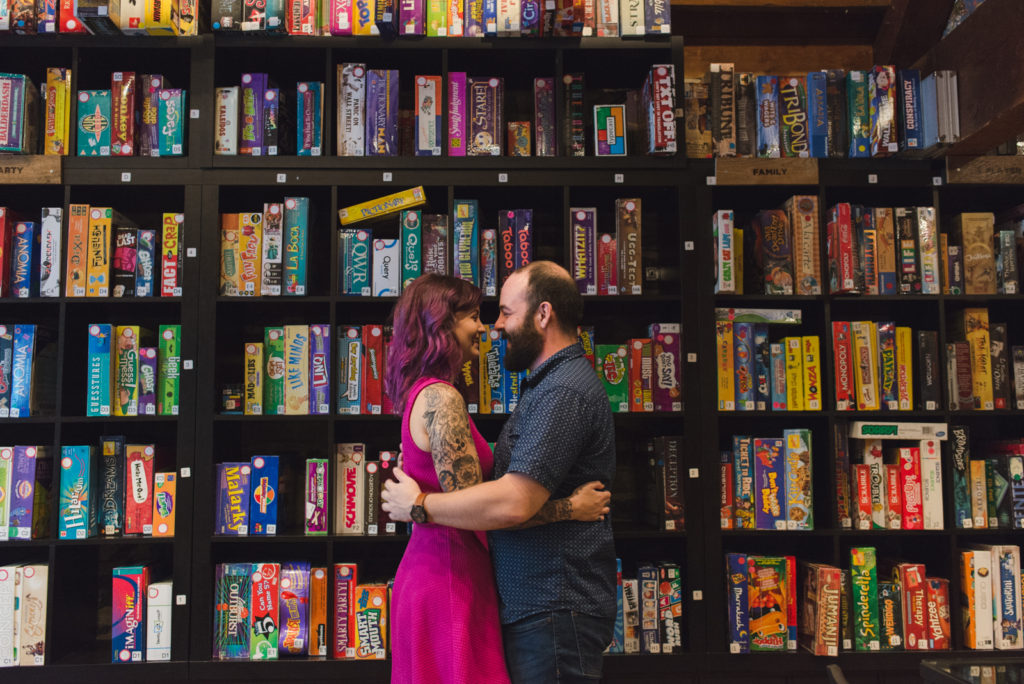 couple cuddling in front of wall of board games