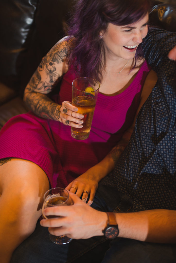 tattoeed girl holding a beer smiling at her fiancee
