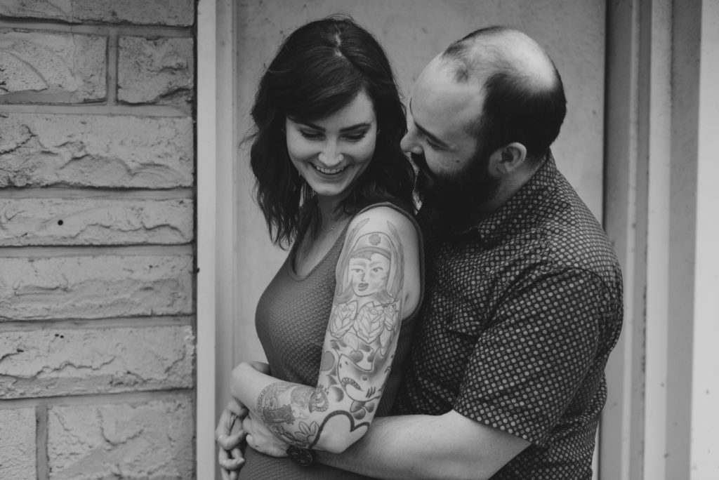 tattoeed couple cuddling in front of old building
