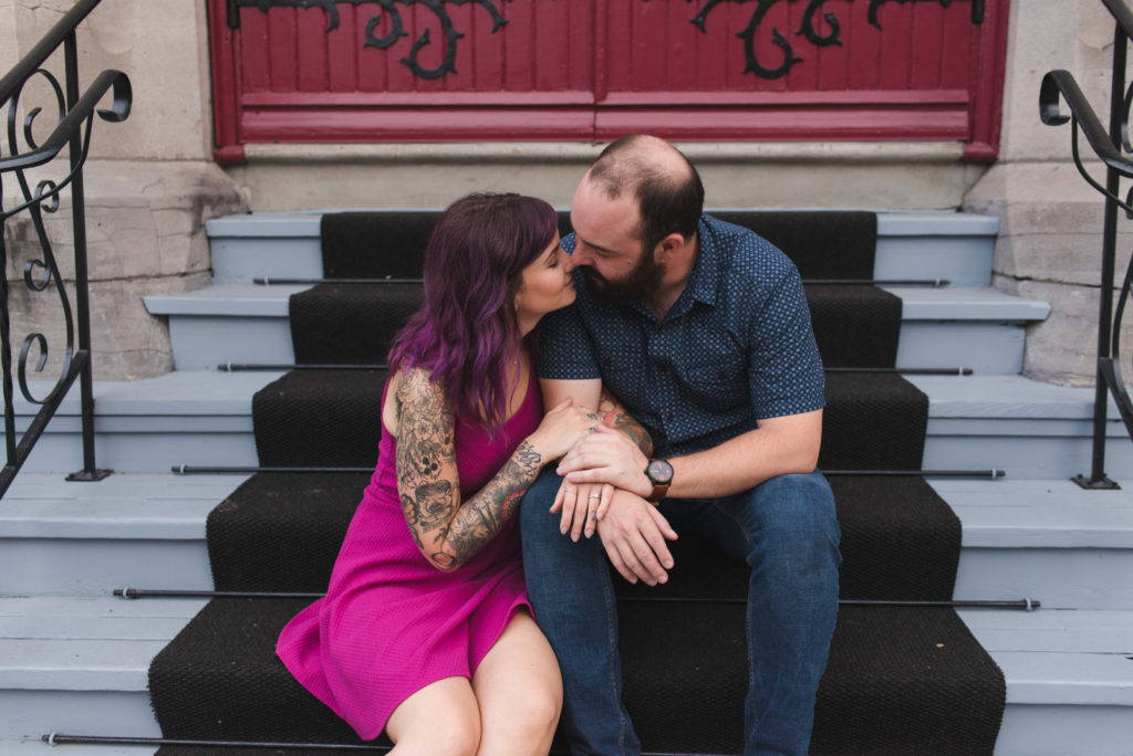 engaged couple almost kissing sitting on steps of church