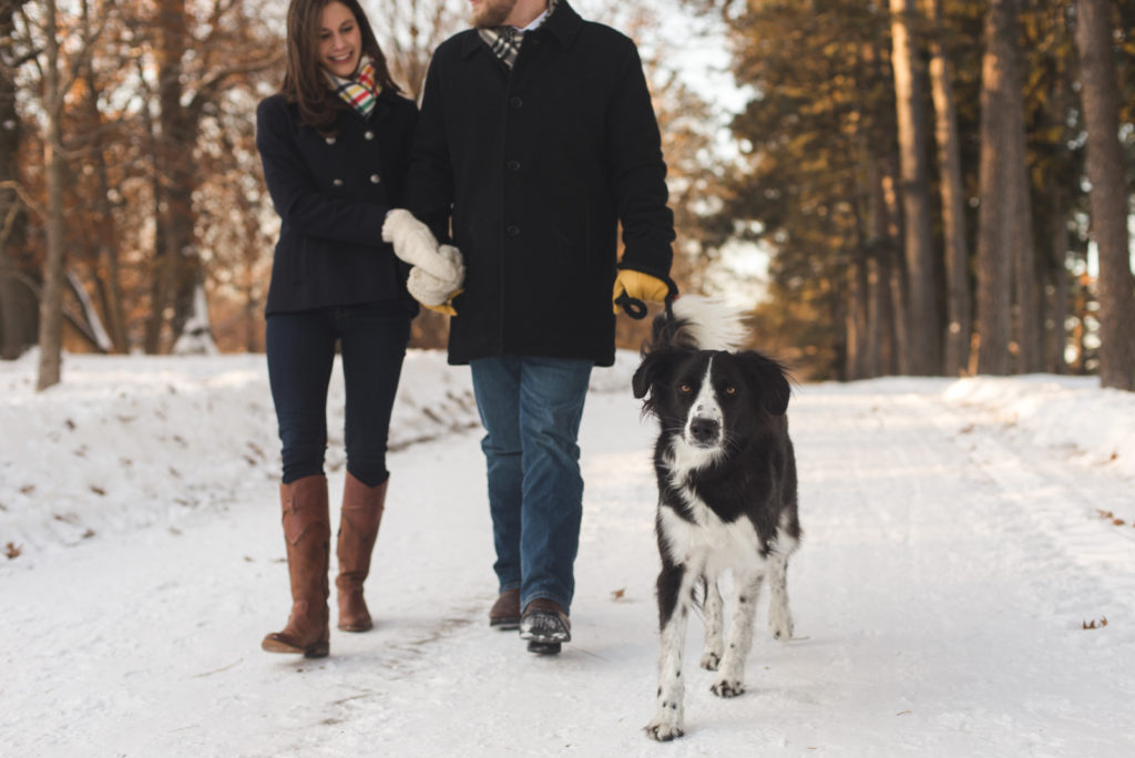 couple walking their dog along a snowy path