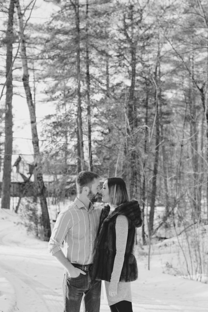 engaged couple kissing on a snowy wooden path