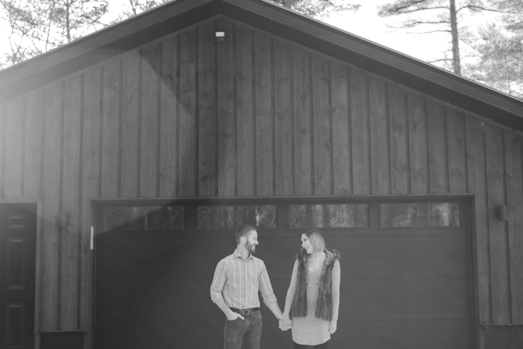 engaged couple standing in front of wooden garage