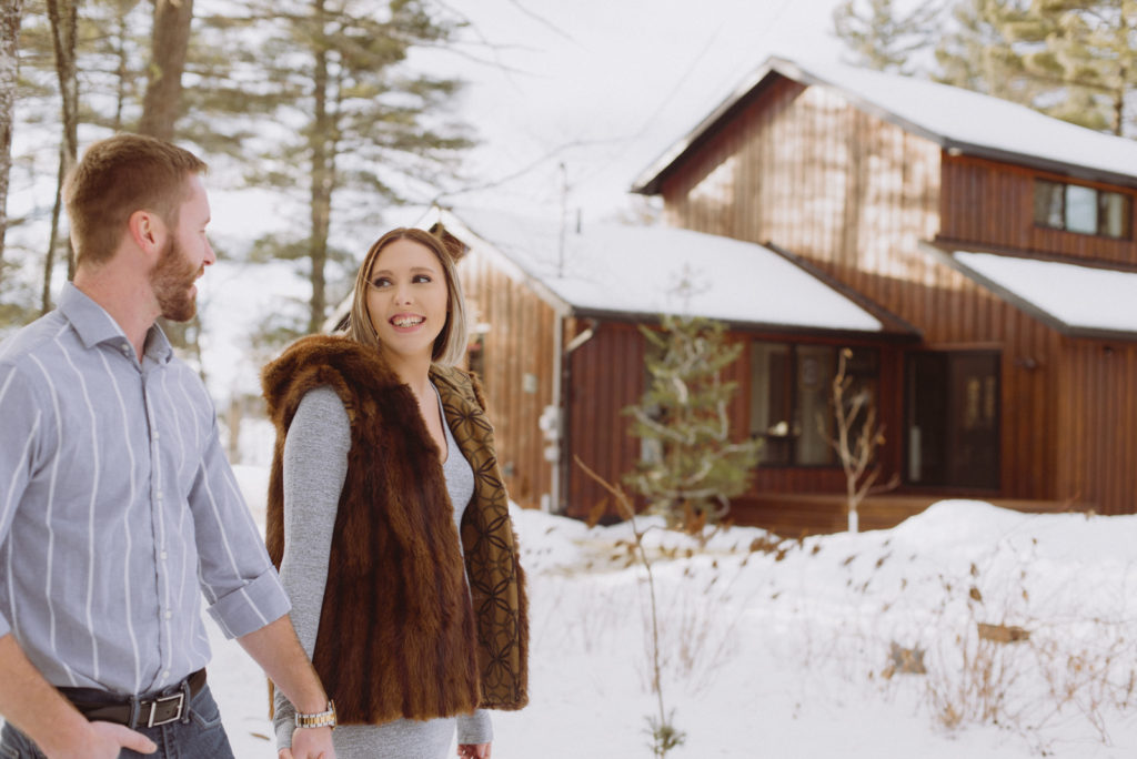 engaged couple walking outside their cottage during winter
