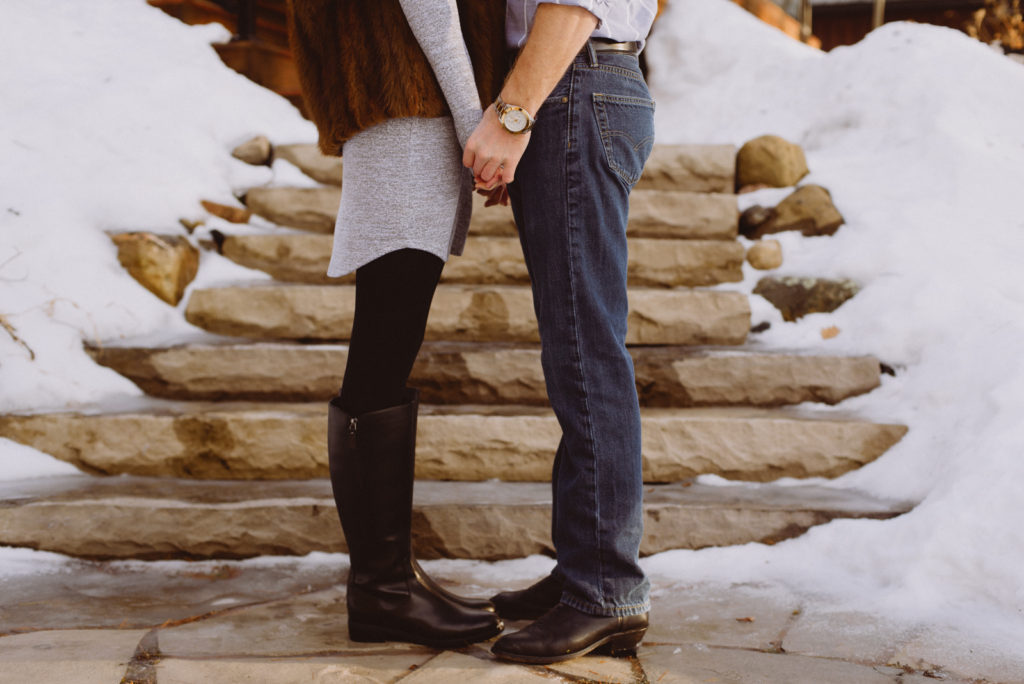 engaged couple standing at the bottom of stone steps holding hands