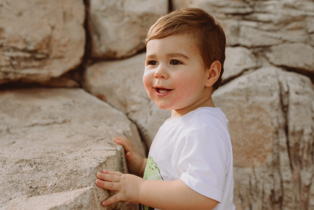 Little boy standing by rocks