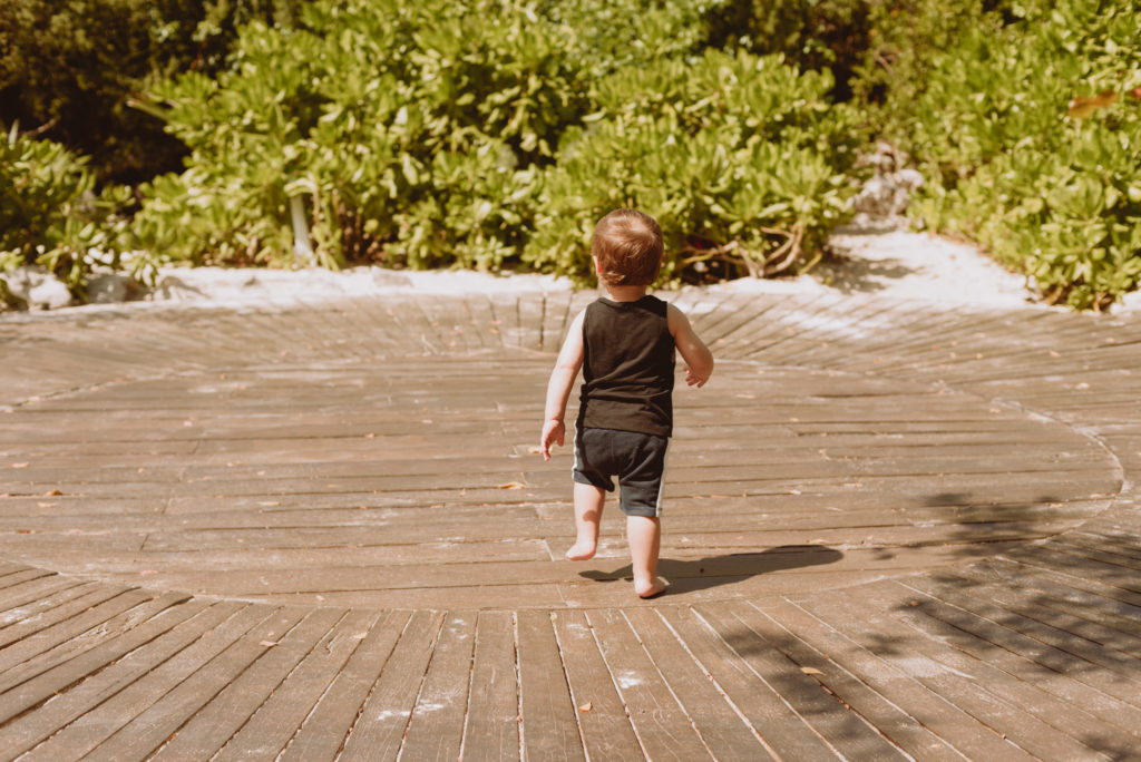 little boy running towards palm trees