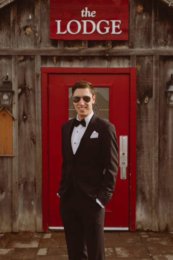 groom standing in front of the Lodge at Strathmere wearing aviator sunglasses
