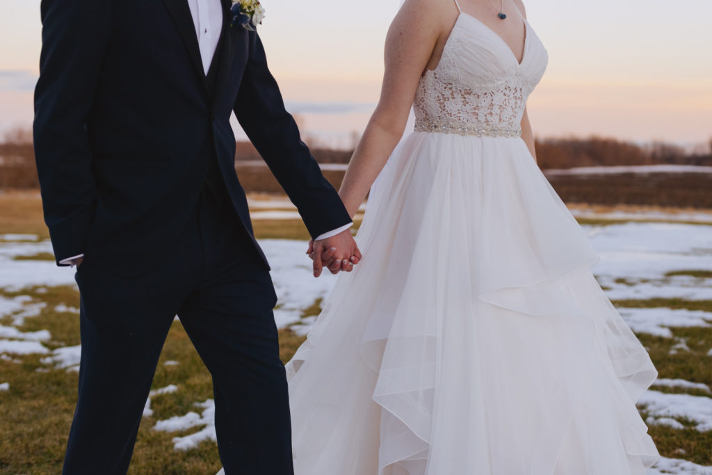 bride and groom holding hands in a snowy field