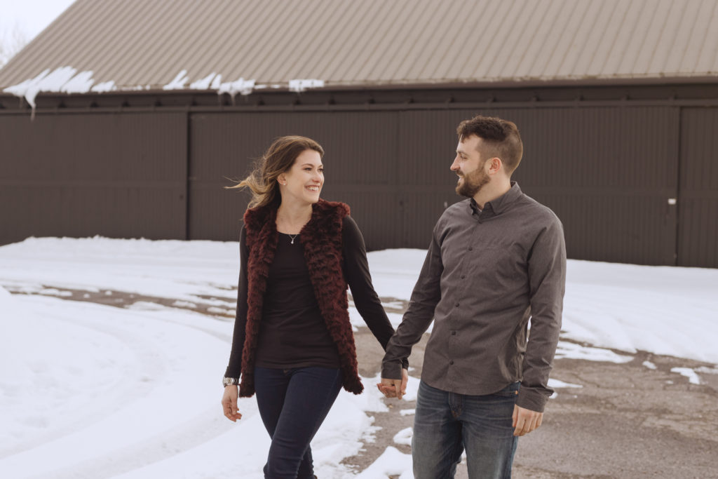 couple walking around snowy path holding hands