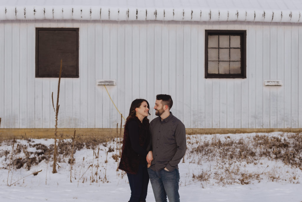 couple cuddling in front of snow covered building