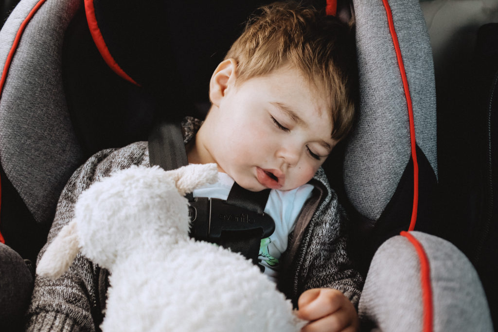 toddler asleep in car seat with stuffed animal