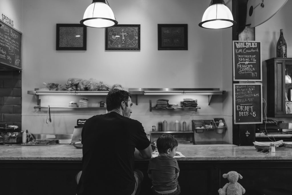 Father and son sitting at the bar of Three Pickles sandwich shop