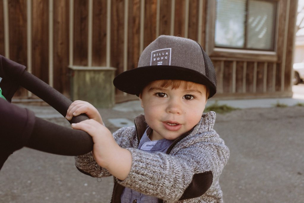 little boy wearing Billabong hat pushing his stroller